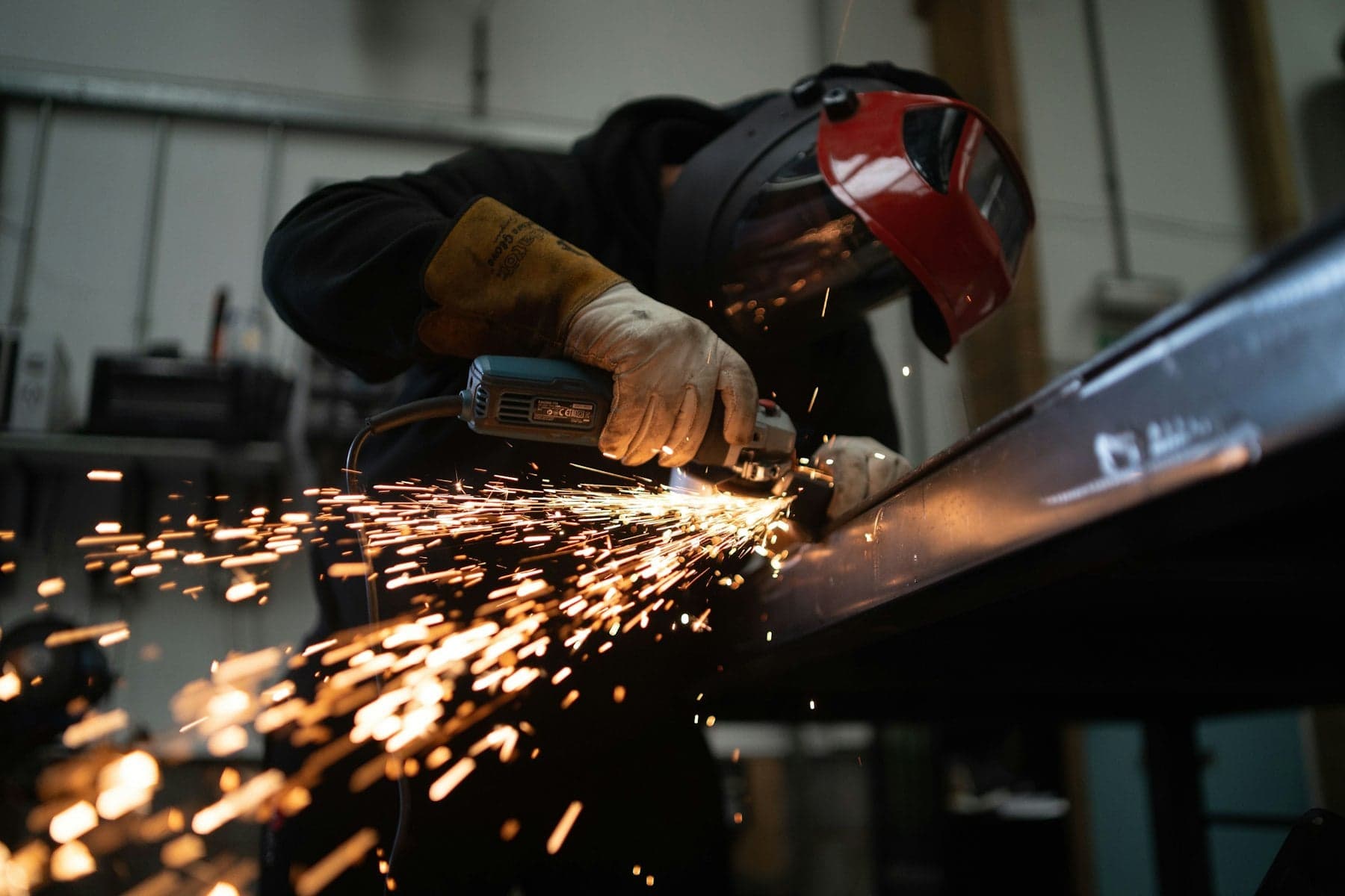Fabricator grinding a steel gate frame flush in the shop
