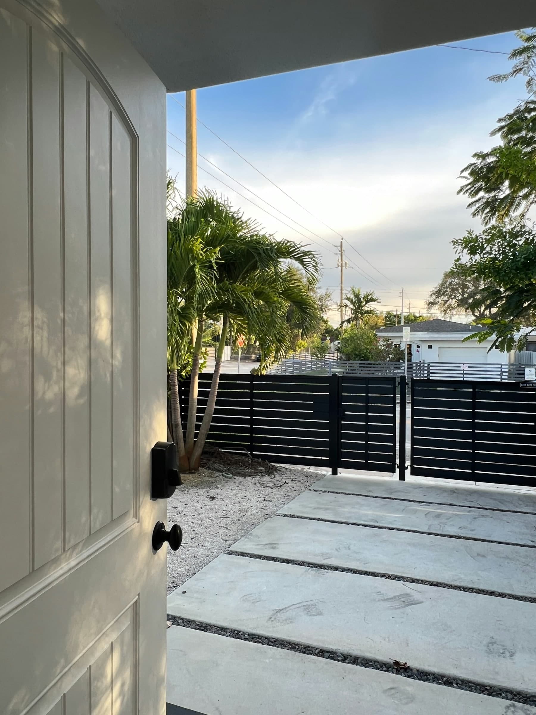 Horizontal slat gate and fence at the side of a modern rendered house