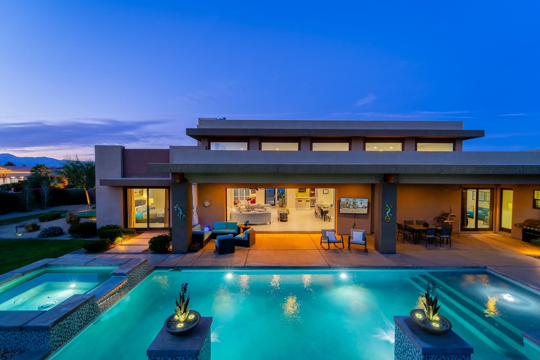 South Florida estate at dusk behind a lit custom entrance gate