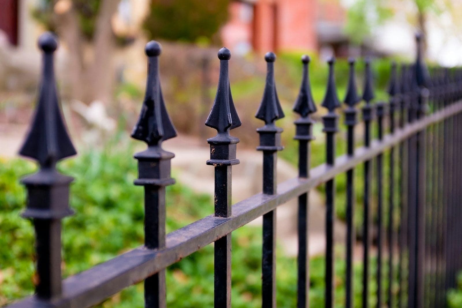 Close view of cast spear-top finials on a black ornamental iron fence