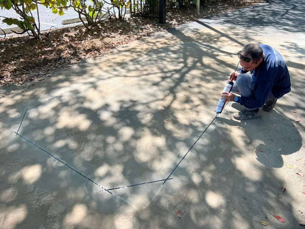 Technician sealing the finished underground loop cut in the same restored driveway
