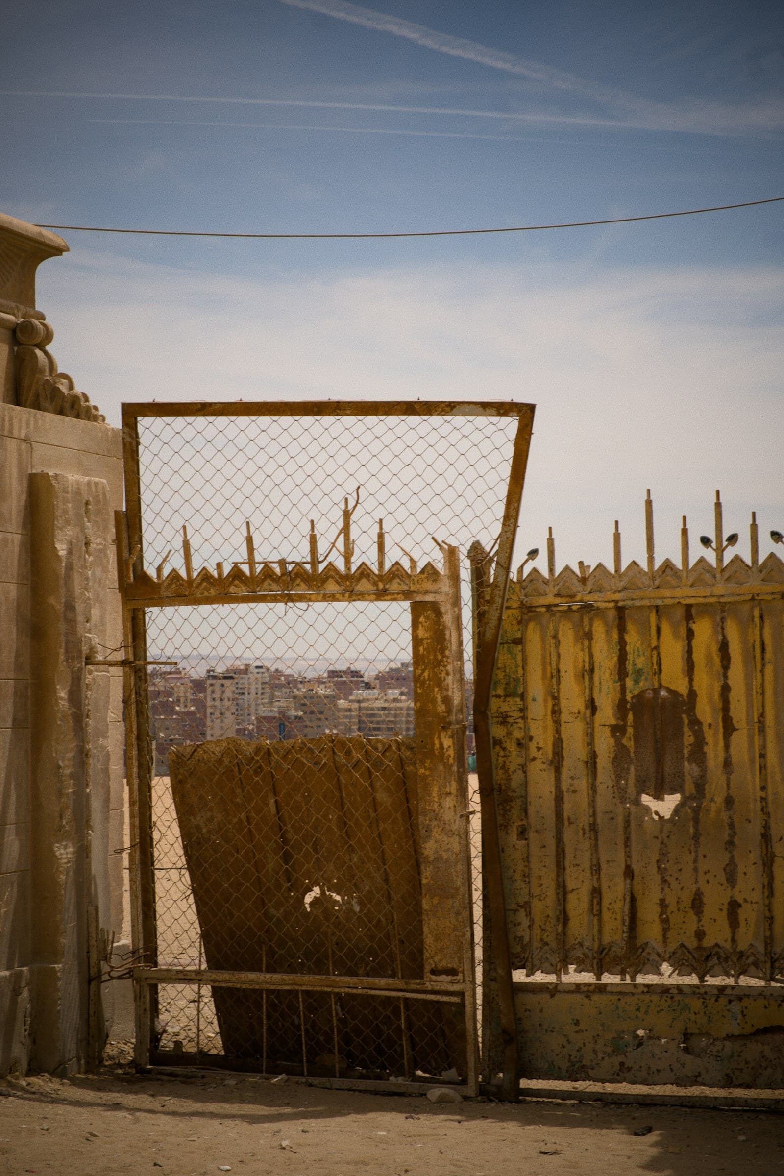 Weathered timber gate with split boards leaning against a chain-link fence