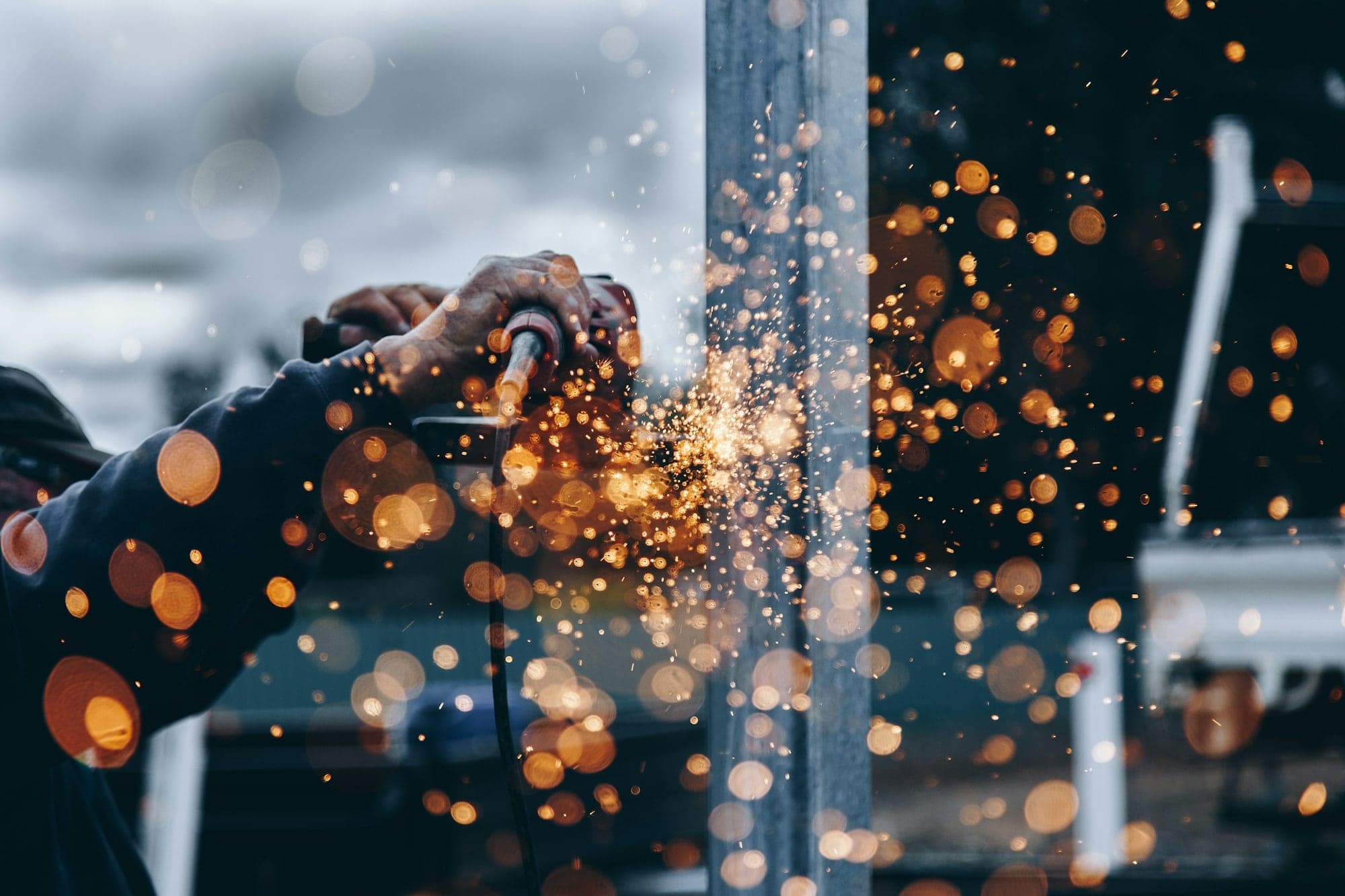 Sparks falling in front of a metal fence panel being worked on