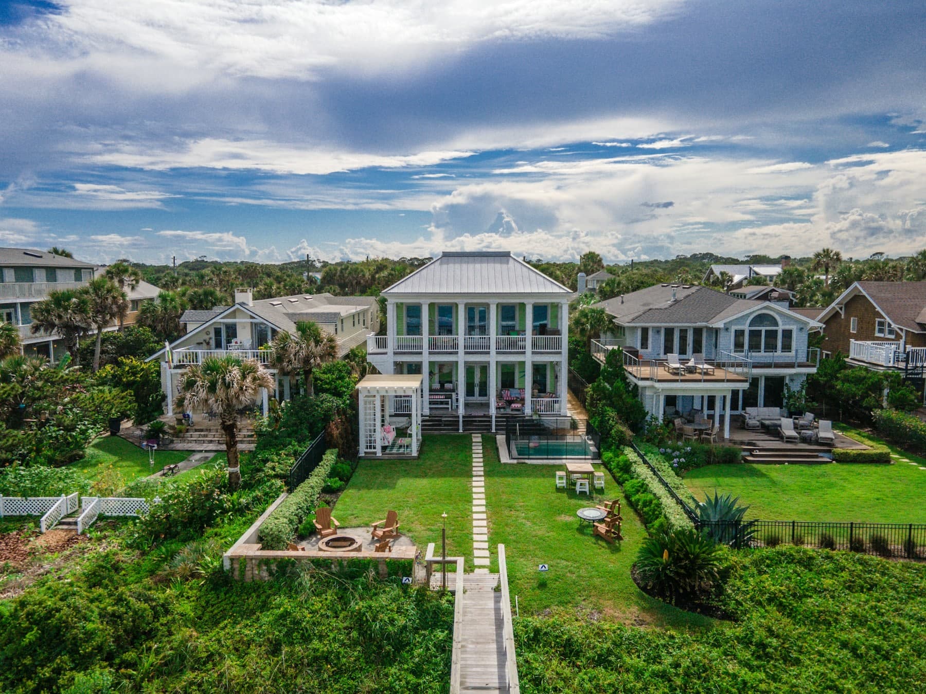Aerial view of a coastal residential street, its rear gardens enclosed by hedging and fencing.