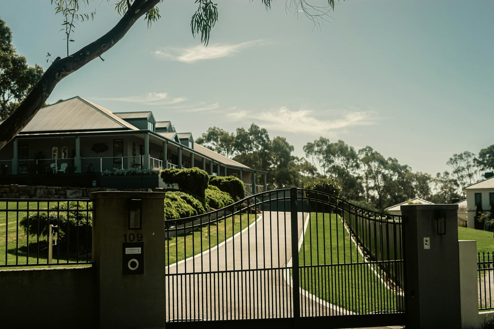 Black metal driveway gate and matching fence across the entrance of a South Florida property