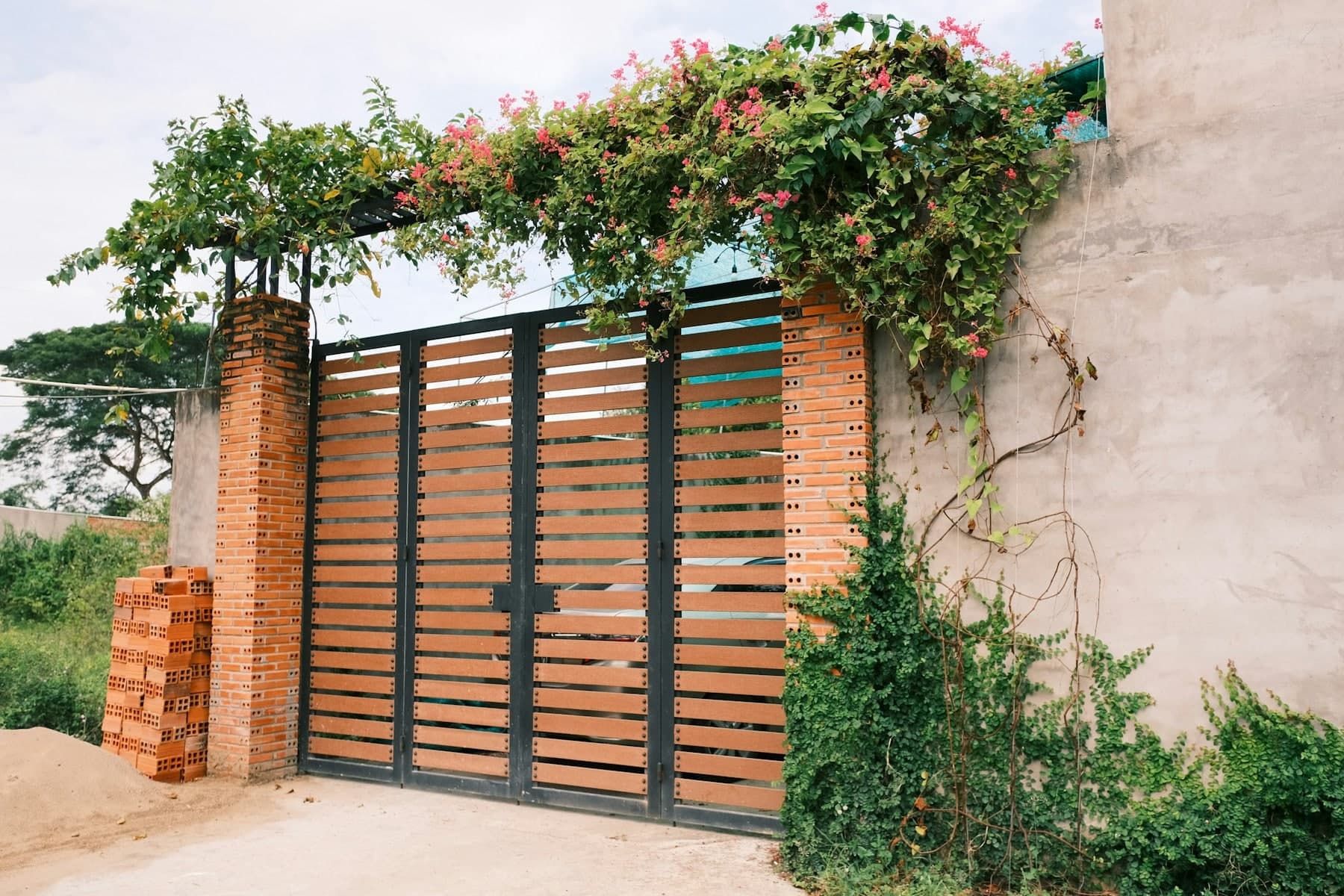 Horizontal timber slat gate between brick pillars under flowering bougainvillea