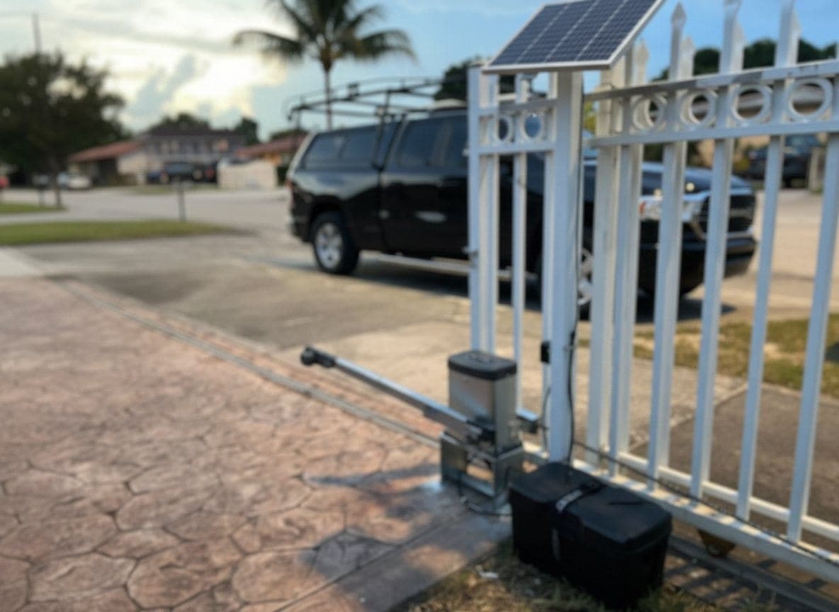 Ram-arm operator and a solar panel fitted to the post of a white aluminum swing gate