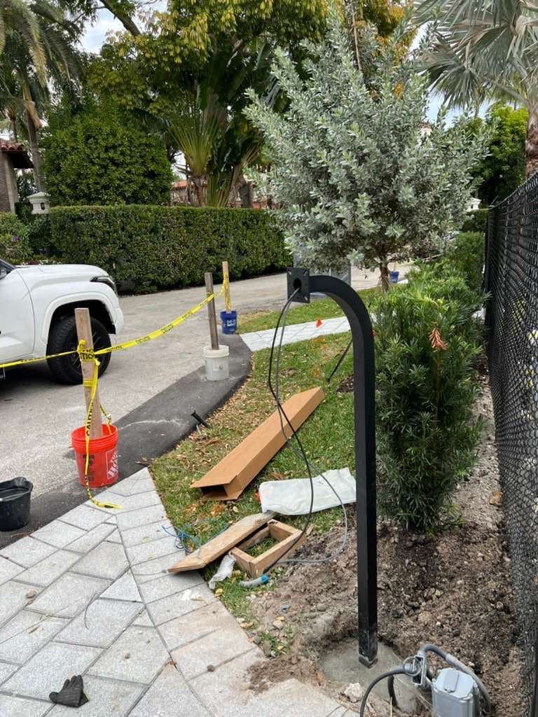 Bare entry post set in the ground with materials on the driveway around it