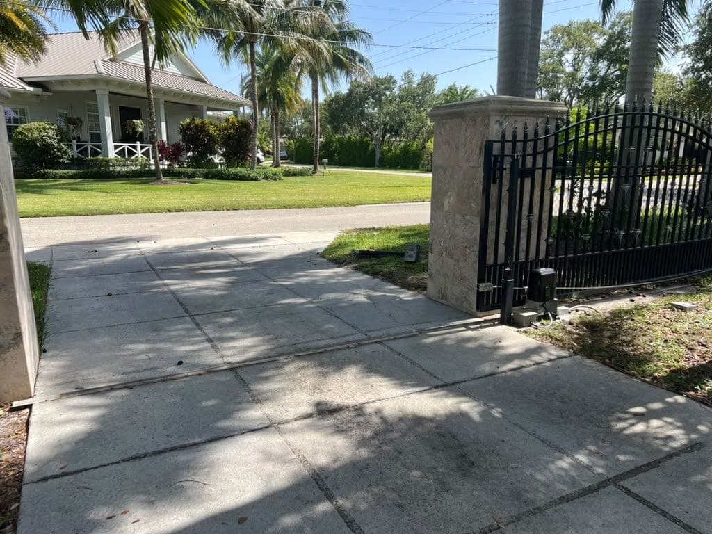 Automated swing gate with its operator arm mounted at the base of a stone pillar