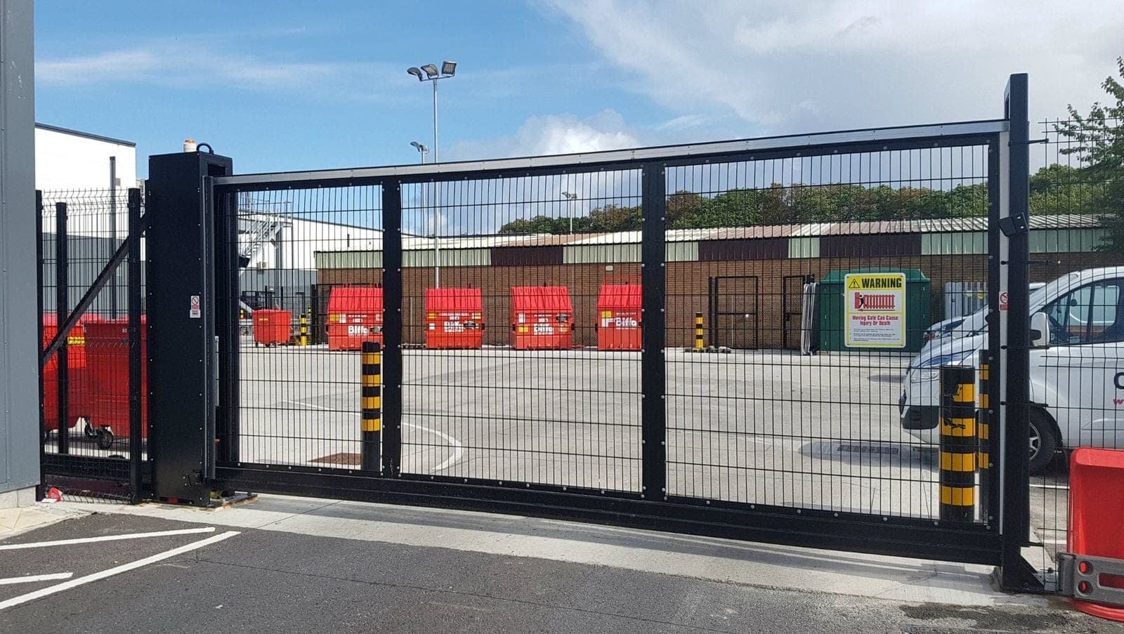 Wide commercial sliding gate across the entrance to a fenced service yard