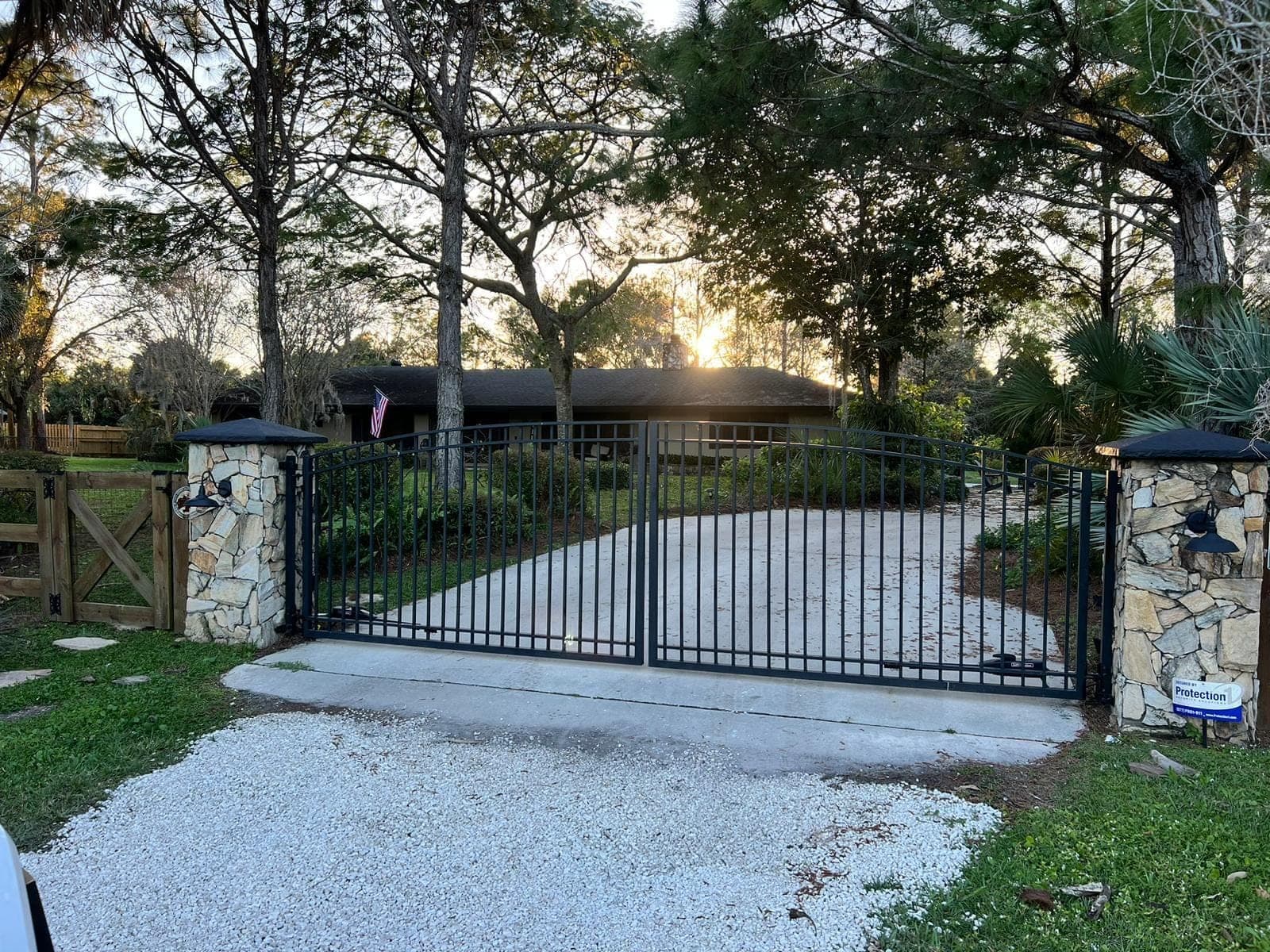 Wide driveway gate and railing photographed at dusk from the street